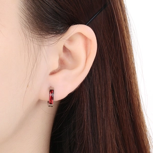 Close-up of model wearing silver hoop earring with rectangular red zircon gemstone