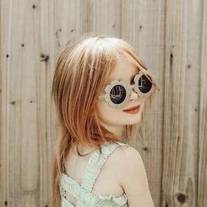 Detail of beige flower-shaped sunglasses on a child with dark sun protection lenses