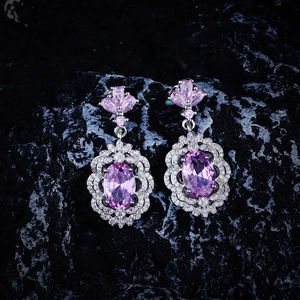 Macro shot of luxurious silver drop earrings with oval purple stones on dark rock