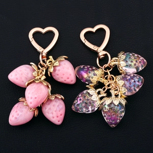Close-up of pink and transparent glitter strawberry keychains with golden heart clasps