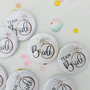 Close-up of white Team Bride tinplate badges with rose gold diamond ring graphics