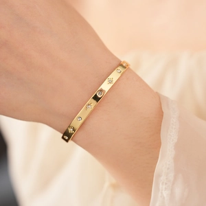 Détail d'un bracelet doré avec gravures en étoile et pierres en oxyde de zirconium