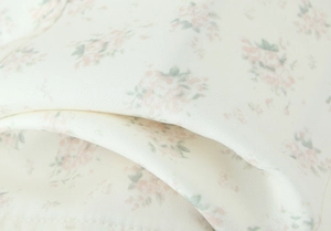 Dettaglio macro del tessuto in chiffon a fiori crema con finitura setosa e leggera