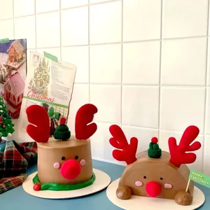Detail of reindeer Christmas cake toppers featuring red antlers and knitted hat decorations
