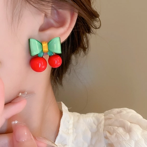 Boucles d'oreilles cerises mignonnes avec nœud vert et fruits rouges sur un modèle