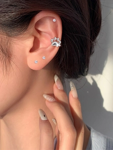 Close-up of a silver cat paw ear cuff and sparkling cubic zirconia stud earring set