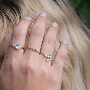 Detailed view of three luxury gold rings featuring blue sapphire and diamonds on fingers