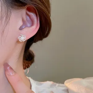 Elegant silver hollow flower stud earrings with a matte texture on a female model