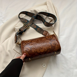 Detail of vintage embossed leather cylinder bag in caramel brown with wide jacquard strap