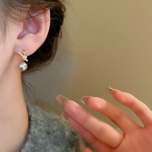 Vintage gold-plated knot earrings with zircons and grey pearl drop on a female model