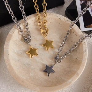 Three gold and silver stainless steel star pendant necklaces on a light stone tray