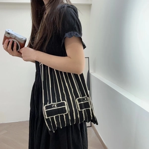 Lifestyle view of a black and white pleated knit tote bag worn by a model