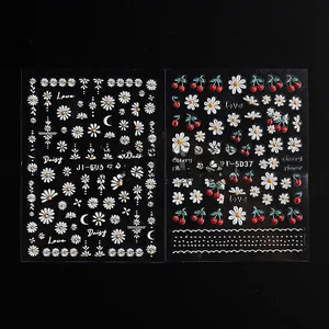 Detailed macro of 5D embossed nail art stickers with white daisy and red cherry patterns