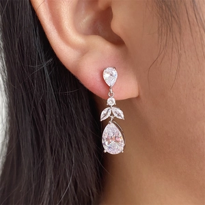 Macro shot of a silver drop earring with sparkling zircon on a model's ear