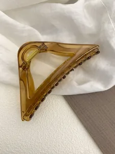 Detail of amber tortoiseshell hair claw with strong golden metal spring and resin teeth