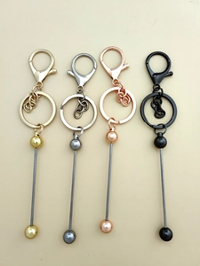 Detail of four metallic DIY beaded keychains in gold, silver, rose gold and black colors