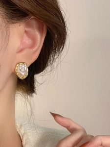 Close-up of French vintage irregular gold earring with white baroque pearl on ear