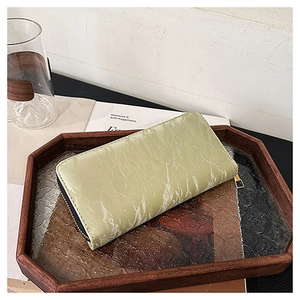 Close-up of light green velvet wallet on a wooden tray in a lifestyle setting