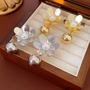 Détail de boucles d'oreilles fleurs avec perles en or et argent sur une boîte à bijoux