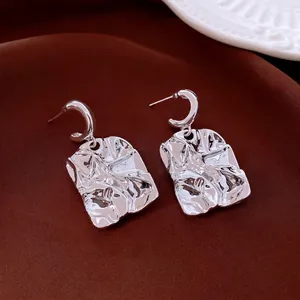 Minimalist silver ginkgo leaf earrings with crumpled texture on dark velvet background