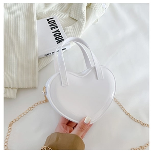 Close-up of white heart-shaped patent leather mini bag with elegant gold chain strap
