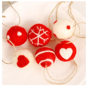 Detail of wool felt Christmas balls with snowflake and heart patterns on white background