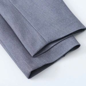 Gros plan sur la texture du tissu sergé gris et les coutures de qualité du pantalon