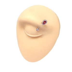 Detailed view of eyebrow ring with red pear-shaped stone and crystal pavé on curved bar