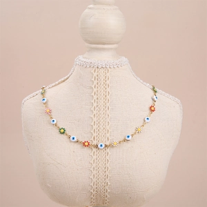 Detail of gold necklace with colorful floral charms and blue evil eye beads on a mannequin