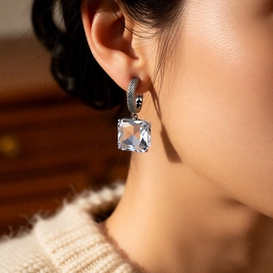 Detail of square-cut crystal earrings with retro textured silver metal on a model
