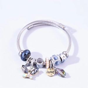 Detail of silver cable bangle featuring black beads, golden LOVE charm, and crystal butterfly