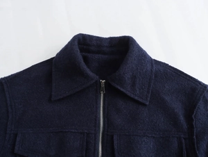 Détail macro du col d'une veste en tweed bleu foncé avec texture laine et zip métallique