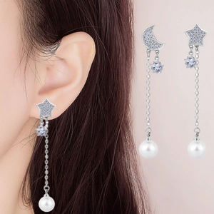 Detailed view of silver star and moon drop earrings with blue rhinestones and pearls