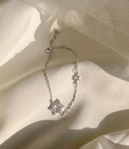 Close-up of silver star bracelet with micro-pave crystals on soft white silk