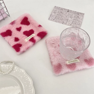 Macro detail of plush pink square coaster with red heart pattern and Sozakka woven label