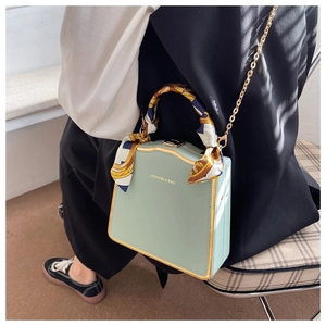 Detail of mint green box bag featuring a gold chain and floral silk scarf handle wrap