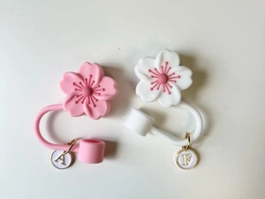 Detail view of silicone cherry blossom straw covers with letter A and F gold charms