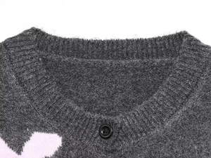 Détail de gilet gris en maille avec col côtelé, bouton noir et texture laineuse douce