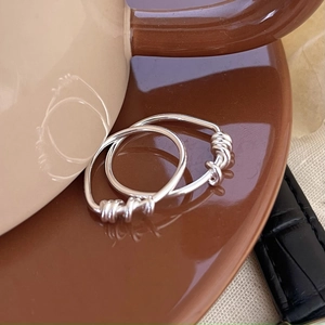 Detail of 925 sterling silver spiral rings set against a ceramic cup, minimalist style