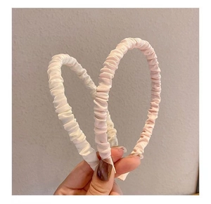 Detail of pink and white satin pleated headbands held in a heart shape for hair styling