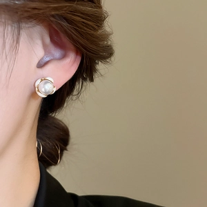 Dettaglio degli orecchini a fiore con perla e bordo dorato indossati con stile francese