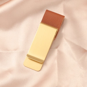 Dettaglio della clip per penna vintage in metallo dorato e pelle marrone su seta rosa