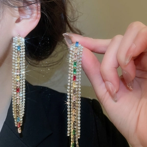 Close-up of elegant colorful zircon tassel drop earrings worn by a model in soft lighting