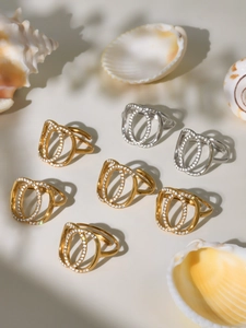 Macro view of double oval intertwined rings with cubic zirconia pavé and gold finish