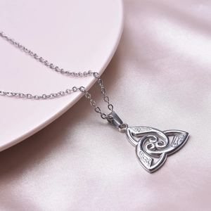 Macro shot of a silver Celtic knot necklace pendant on purple satin fabric