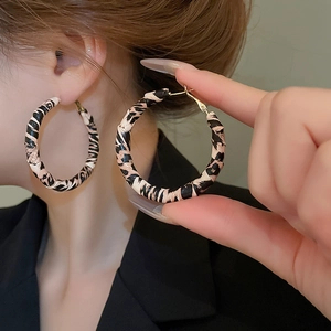 Détail de boucles d'oreilles créoles à imprimé léopard avec tiges dorées à la main