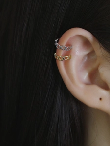 Close-up of heart-shaped ear cuffs in silver and gold finish on a model's ear