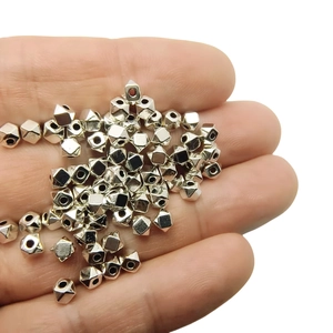 Close-up of geometric faceted Tibetan silver spacer beads held in hand for DIY jewelry