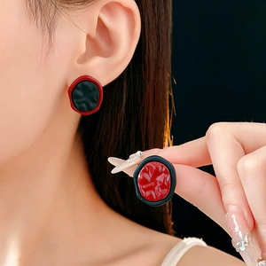 Détail de boucles d'oreilles rondes irrégulières au fini brillant rouge et noir contrasté