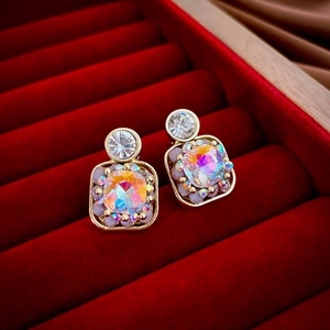 Close-up of vintage gold square earrings with iridescent stones in a red velvet jewelry box